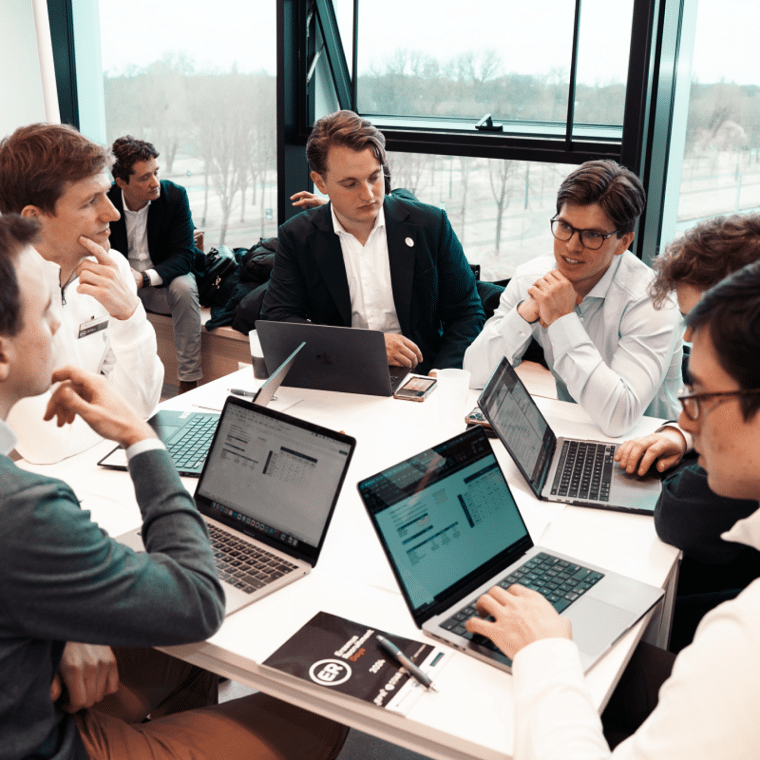 Studenten van Erasmus Recruitment zitten op tafel met laptops voor zich en zijn aan het overleggen.