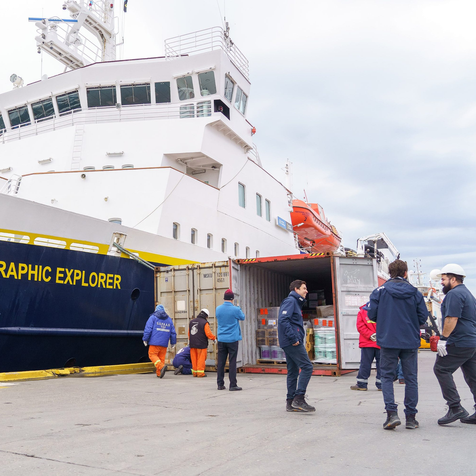 Collega's van Ushuaia shipping staan in gesprek met elkaar naast een scheepsboot