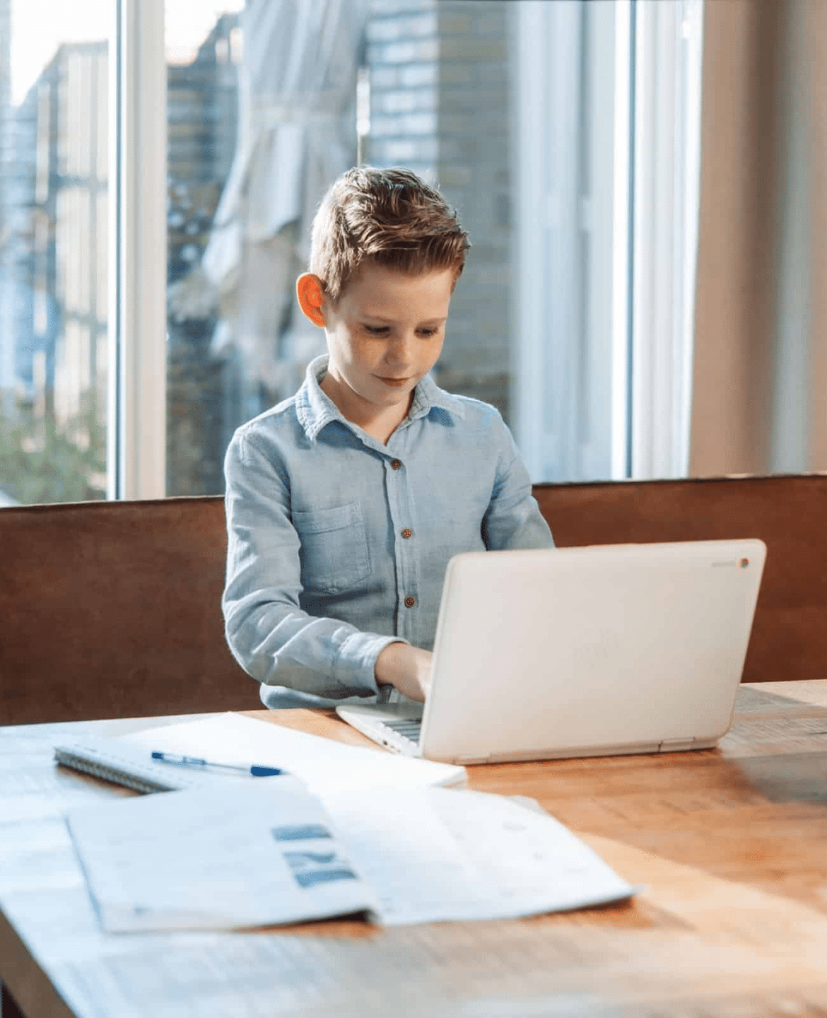 Een jongetje zit achter zijn laptop