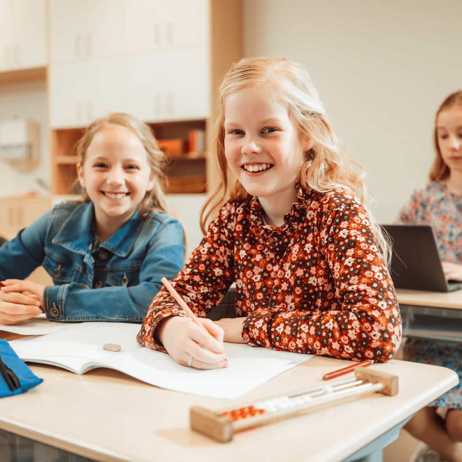 Twee meisjes zitten achter hun bureau op school