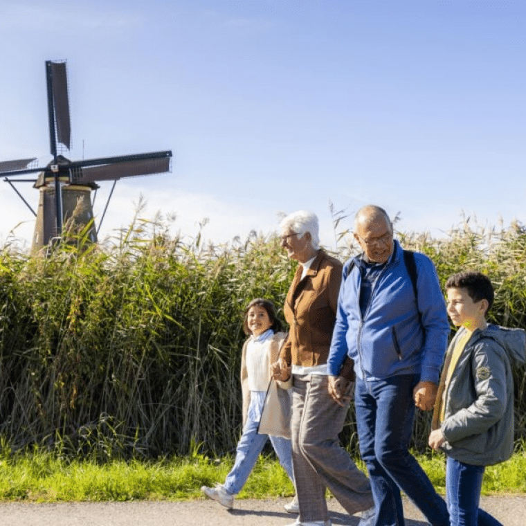 Kinderen wandelen met hun opa en oma door het gebied van Kinderdijk